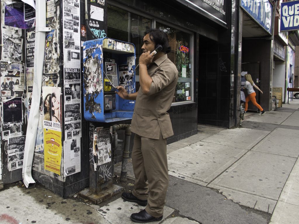 Man on payphone while woman runs into a store