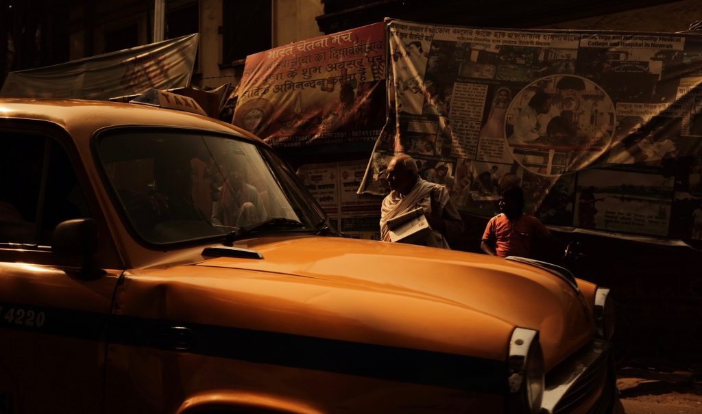 man standing behind car all with an orange tint photographed using zone photography