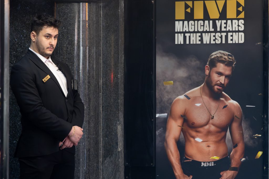 man in a suit standing next to a poster