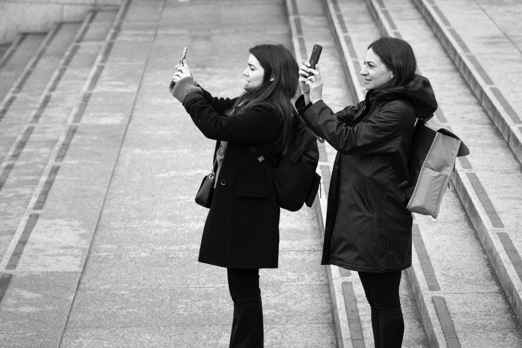 two girls dressed the same using camera phones